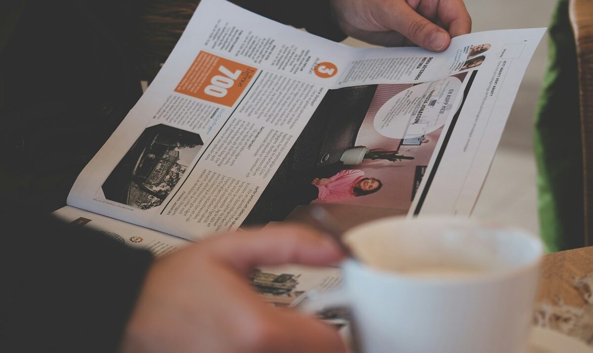 person reading while holding white ceramic mug